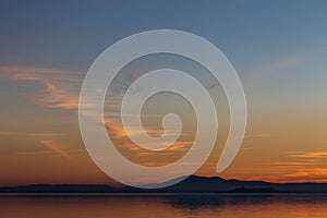 Beautiful view of Trasimeno lake Umbria, Italy at sunset, with orange and blue tones in the sky