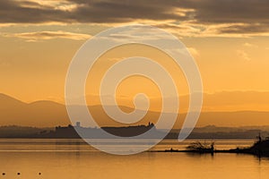 Beautiful view of Trasimeno lake Umbria, Italy at sunset, with orange tones, birds on water, a man on a canoe and