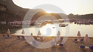 Beautiful view of tropical beach with chairs, umbrellas and moored yachts