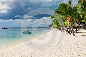 Beautiful view of the tropical beach in Mauritius. Transparent ocean, sand beach, palms and boats