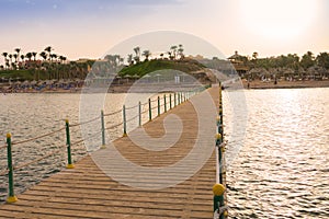 Beautiful view of the tropical coast with a long pantone. A large wooden pier is on the sandy beach of the resort. Landscape of