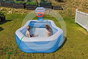 Beautiful view of two boys in inflatable outdoor swimming pool playing water basketball on sunny summer day.