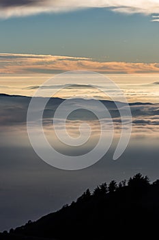 Beautiful view of Umbria valley Italy covered by a sea of fog at sunset, with beautiful warm colors and trees