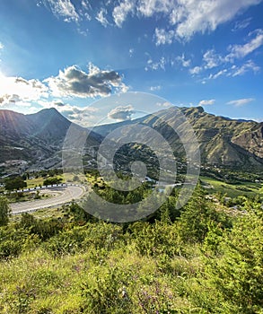 Beautiful view of the valley in the mountains with a road and a river on a sunny summer day. Dagestan