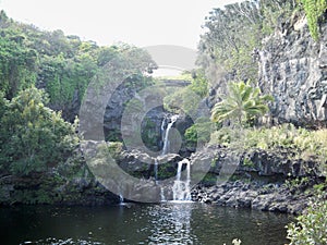 Beautiful view of a waterfall pouring in the middle of mountainous scenery in Hawaii