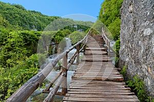 Beautiful view of waterfalls with turquoise water and wooden pathway through over water. Plitvice Lakes National Park, Croatia. Fa