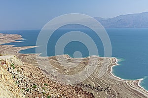 Beautiful view of the whimsically shaped sandy and salty coastline of the blue dead sea in Israel.