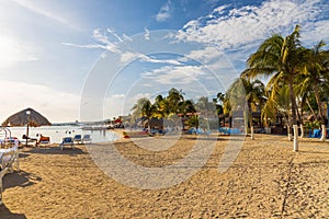 Beautiful view of white sand Curacao beach. Blue sunbeds under sun umbrellas on turquoise water and blue sky.