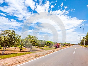 Beautiful view of wide open road with a paved highway stretching out as far as the eye can see with small green hills