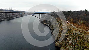 Beautiful view on a wide river with cliffs on its shore, amazing bridge with traffic on it, 4k