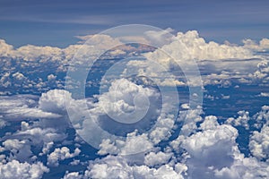 Beautiful view from window of plane flying over clouds. White clouds moving above the ground.