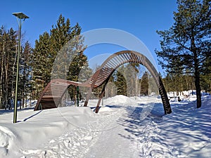 Beautiful view of a wooden installation and a path in a snowy city park. Noyabrsk, Russia