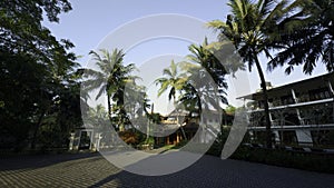 Beautiful villa against blue cloudy sky. Action. Palm trees and green grass.