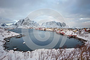 Beautiful village of Reine in Lofoten Islands, Norway. Snow covered winter landscape at sunset. Amazing tourist attraction in the