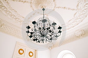 Beautiful vintage chandelier in the living room with ornamental ceiling