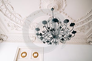 Beautiful vintage chandelier in the living room with ornamental ceiling