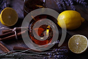 Beautiful vintage composition with herbal tea, lemon, cinnamon stick and lavender on a natural background. Dark wooden backdrop