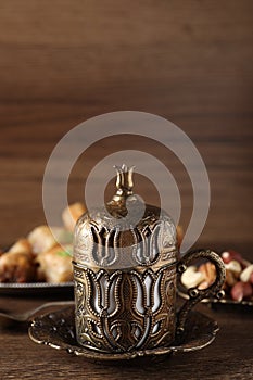 Beautiful vintage cup holder, nuts and baklava dessert on wooden table, space for text