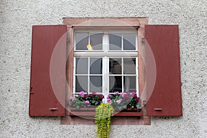 Beautiful vintage European window with red shutters and flower box