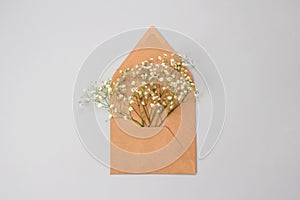 Beautiful vintage flat lay minimal composition with kraft paper brown envelope with gypsophila Baby`s-breath flowers inside on