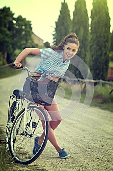 Beautiful vintage girl sitting next to bike, summer time