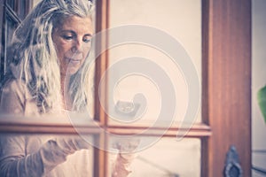 Beautiful vintage old style portrait of alternative senior woman typing and reading a mobile phone device at home viewed from the