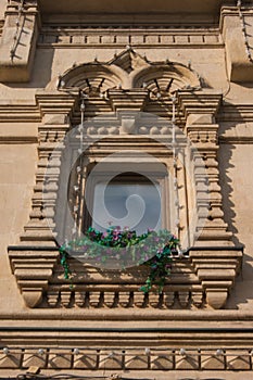 Beautiful vintage window on an old building with fresh flowers on a windowsill