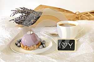 Sweet morning breakfast time concept, beautiful violet cake, blueberries, cup of coffee near plate with the note I love