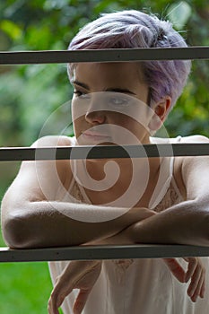 Beautiful violet short-haired girl behind a fence looking at her