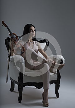 Beautiful Violinist Woman sitting with electric violin on the ch