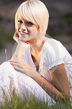Beautiful vivacious blond sitting in long grass