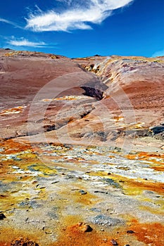 Beautiful volcanic icelandic landscape, yellow, orange and white geothermal field with sulfur deposits, fissure in red stone,