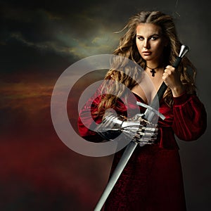 Beautiful Warrior Woman with Sword. Medieval Female Knight in Red Dress with Armor Glove. Beautiful Viking Girl in Fantasy Gown