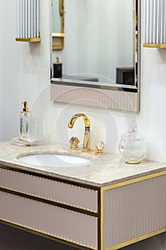A beautiful washbasin with a gold tap and fittings. Marble sink, round led mirror