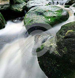 Beautiful waterfall flowing down from moss-covered rocks in the forest, wildlife of Scotland