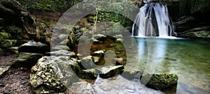 Beautiful waterfall flowing down from moss-covered rocks in the forest, wildlife of Scotland