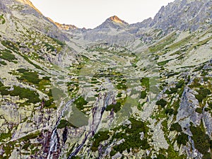 Krásny vodopád tečúci z vrcholu kamennej steny. Vodopád Skok. Mlynická dolina s kamenným turistickým chodníkom. Vysoké Tatry