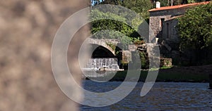 Beautiful waterfall flowing under old medieval bridge in rural Portugal. Slider reveal shot.