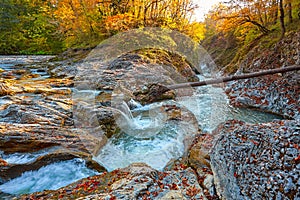 Beautiful waterfall in forest at sunset. Autumn landscape, fallen leaves