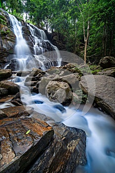 Beautiful waterfall in green tropical forest. View of the falling water with splash in rain season know as name Tad Mok, Chiang