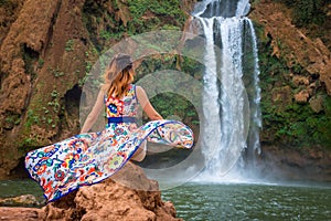 Beautiful waterfall in Morocco. Back of woman in beautiful dress looking fall Ouzoud. Exotic nature of North Africa,