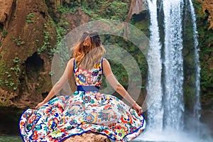 Beautiful waterfall in Morocco. Back of woman in beautiful dress looking fall Ouzoud. Exotic nature of North Africa,