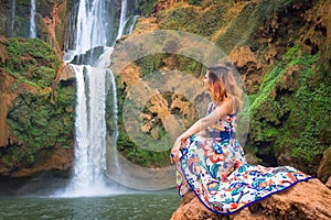 Beautiful waterfall in Morocco. Back of woman in beautiful dress looking fall Ouzoud. Exotic nature of North Africa,