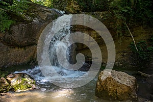 Beautiful waterfall in the mountains. Mountain river. Falling water. Colorful landscape. Beautiful nature. Sunlight.