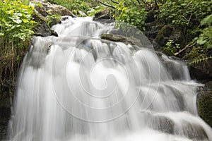 Beautiful waterfall in the mountains. Silky water flows down the rocks. Long exposure