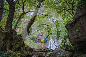 Beautiful waterfall with one person holding an umbrella standing looking
