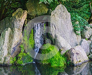 Beautiful waterfall with streaming water with big stones and some covered with green moss peaceful nature scenery background
