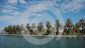 Beautiful waterfront with wonderful palm trees on the background of blue waters of bay and cloudy sky,sunny isles beach