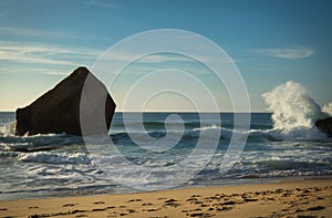 Beautiful wave water splash behind blockhouse on scenic beautiful sandy beach seascape with splashing waves