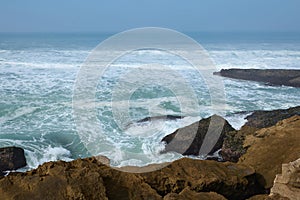 Beautiful waves making sea foam while pounding on rocks and cliff of the Atlantic ocean shore.